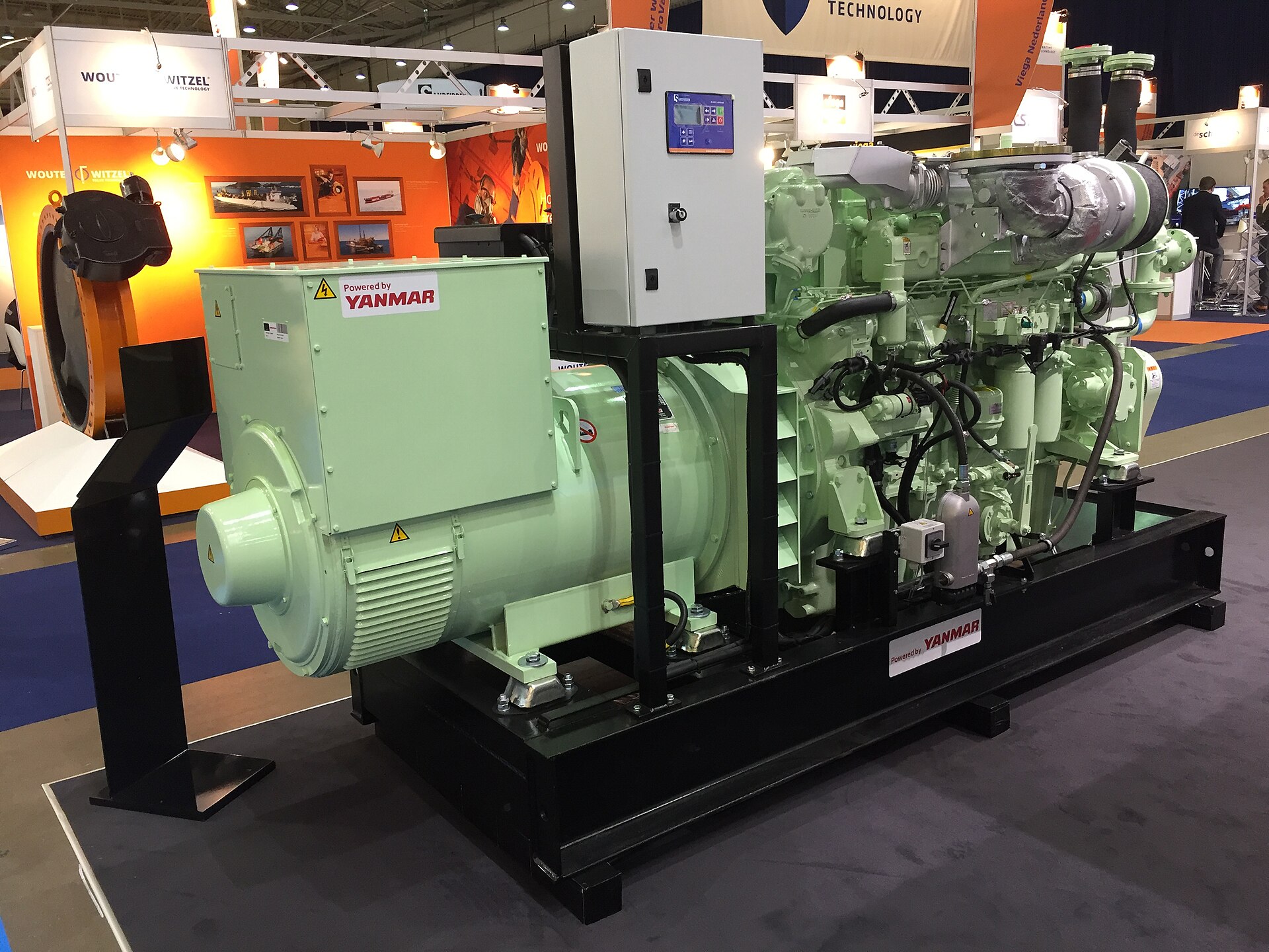 A green diesel generator set on a black base frame at a trade show